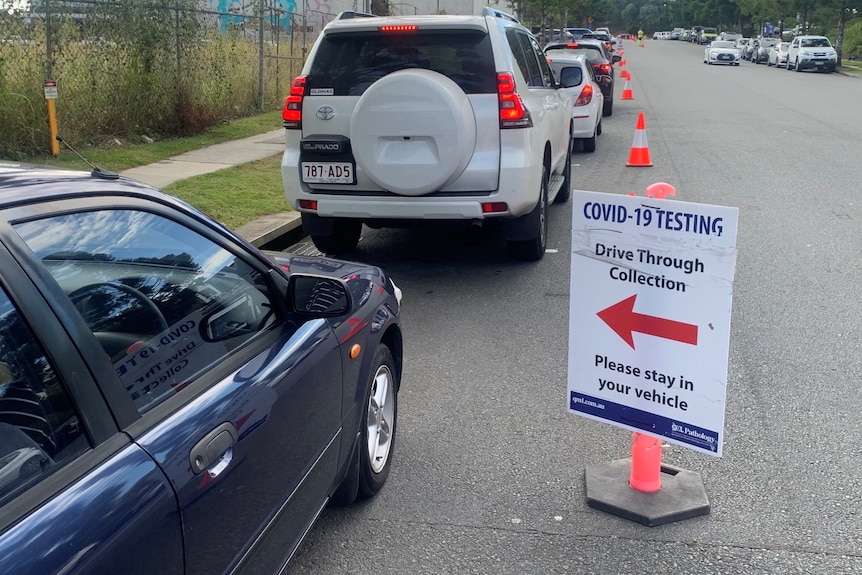 Sign pointing to COVID-19 testing drive through collection with cars lined up