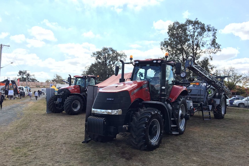 Two red tractors parked on grass at an agricultural show.