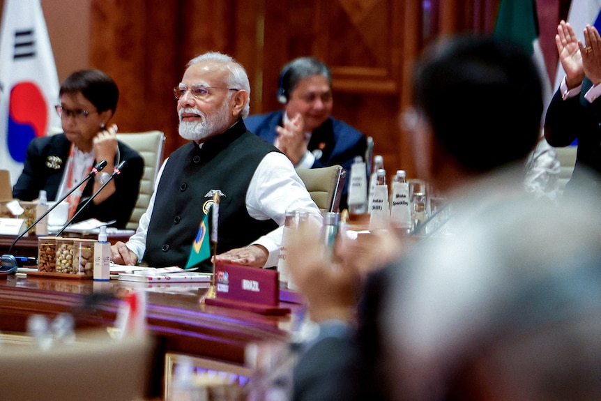 Narendra Modi sits at a table at the G20. 