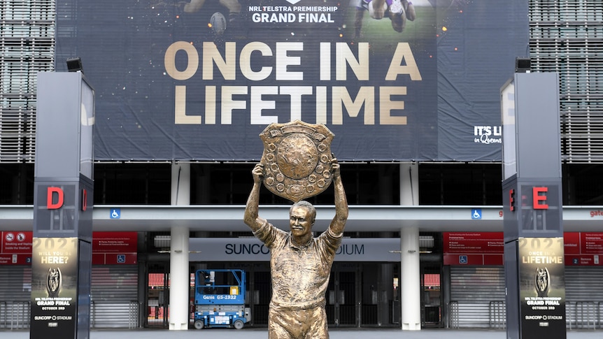 Wally Lewis statue in front of a banner at Lang Park saying "once in a lifetime"