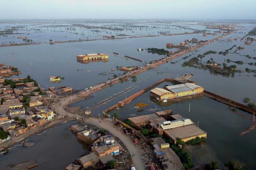 Homes are surrounded by floodwaters in an aerial shot of an innundated area.