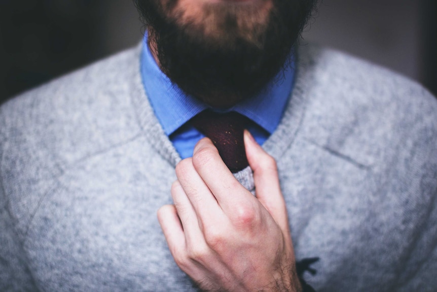 Close up of man with beard doing up his tie, representing classic clothing styles that are ethical fashion for their longevity