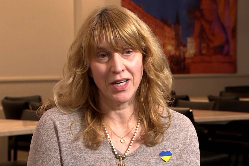 A woman wearing a heart badge with Ukrainian colours.