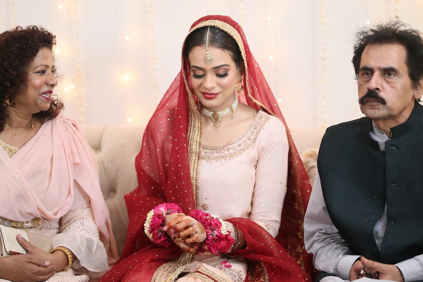 In Karachi, Pakistan, the bride, Hani Ali, is seated between the groom’s parents at her online wedding. 