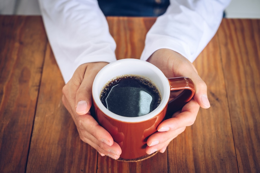 Hand cradling a cup of coffee