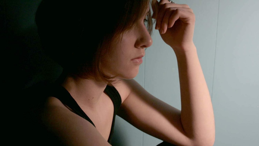 A young woman sits in shadow.