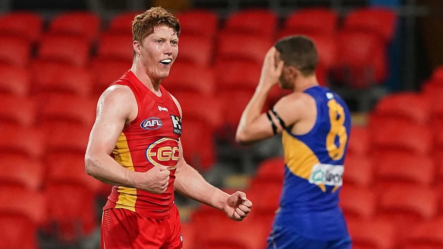 A young AFL player pumps his fists in celebration at the end of a game.