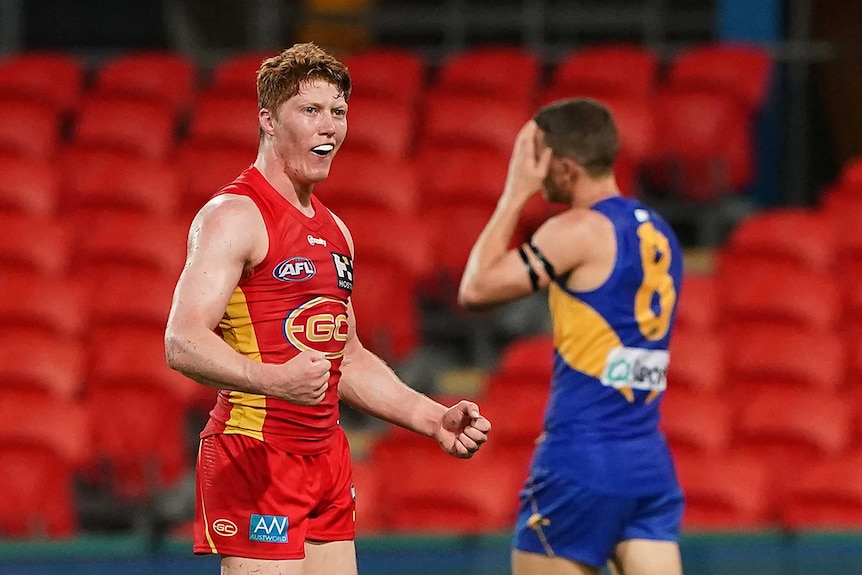 A young AFL player pumps his fists in celebration at the end of a game.