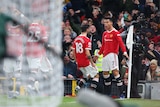 A star footballer stands, with mouth open, at the corner flag as his teammates rush toward him after his Premier League goal.