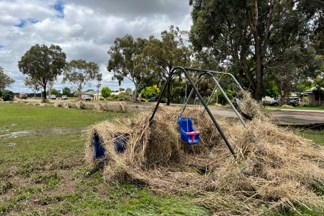 A childrens swing set sits among rubble left by flash flooding. 