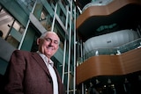 Man stands inside building, posing for camera