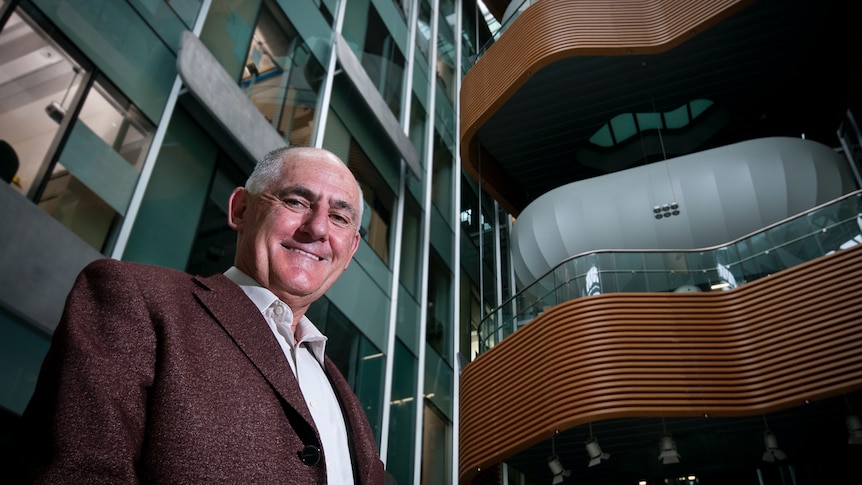 Man stands inside building, posing for camera