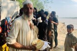 A flood-affected older man gets free food in Pakistan