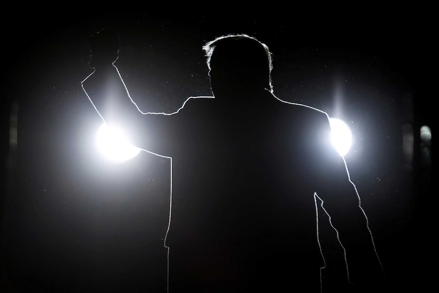 U.S. President Donald Trump is silhouetted as he holds a campaign rally