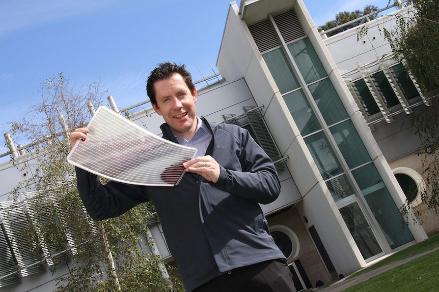 Dr Scott Watson holds a sheet of flexible solar cells