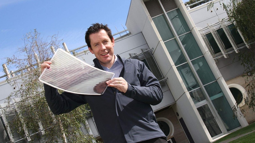 Dr Scott Watson holds a sheet of flexible solar cells
