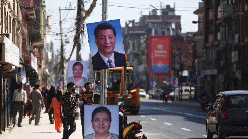 Workers hang portraits of Chinese president Xi Jinping and Nepalese President Bidhya Devi Bhandari