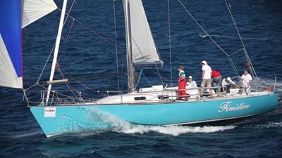 Crew members stand on board Finistere as it sails on the ocean.