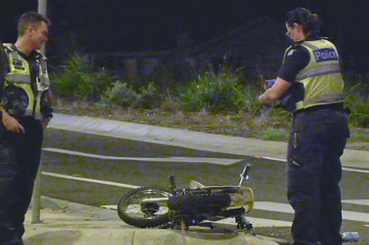 Police officers inspect a motorcycle after it hit an unmarked police car in Melbourne's south.