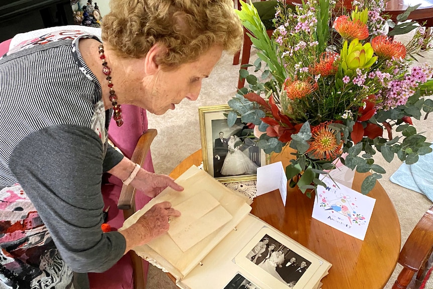 Woman looks at older wedding album, flowers in the background