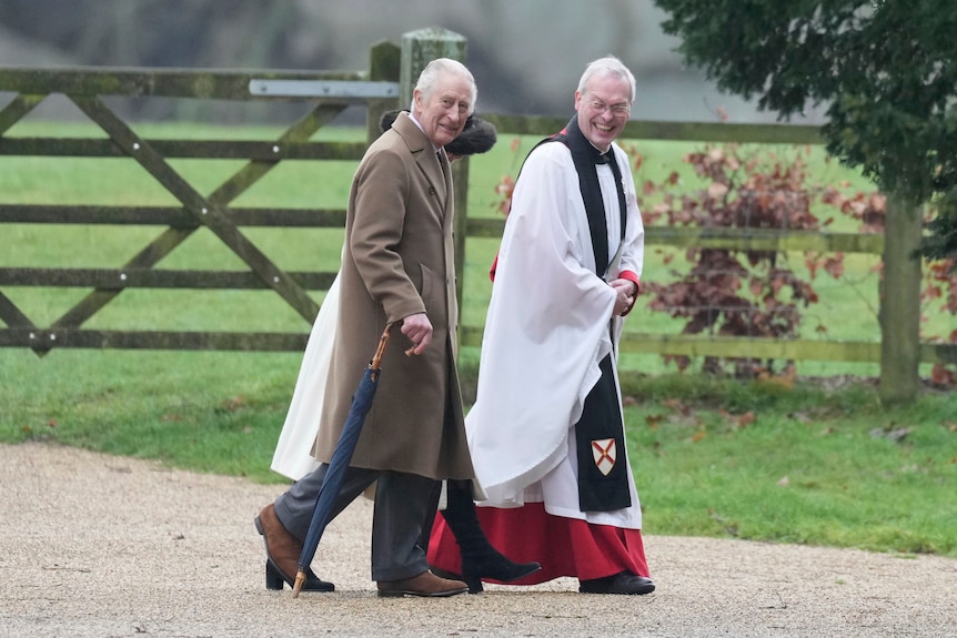 King Charles walks alongside a clergyman in formal wear 