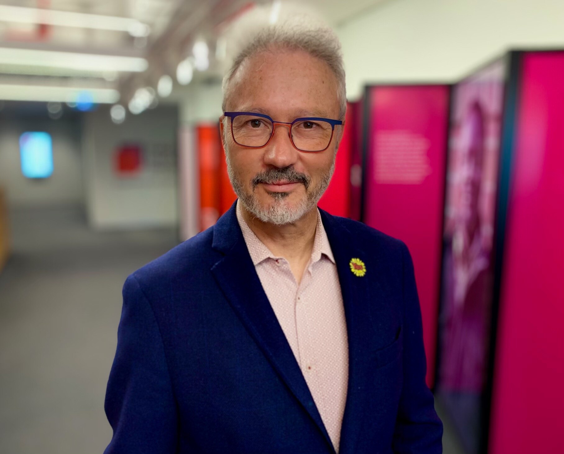 Man wearing glasses and wearing a navy blazer. 