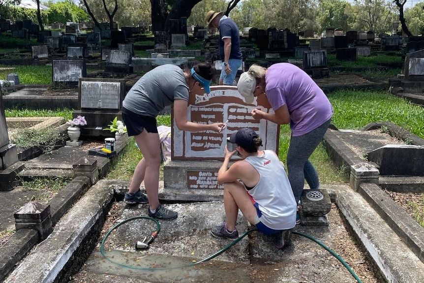 Men and women restoring damaged gravestones