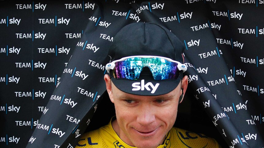 Team Sky cyclist Chris Froome emerges through a curtain wearing the yellow jersey
