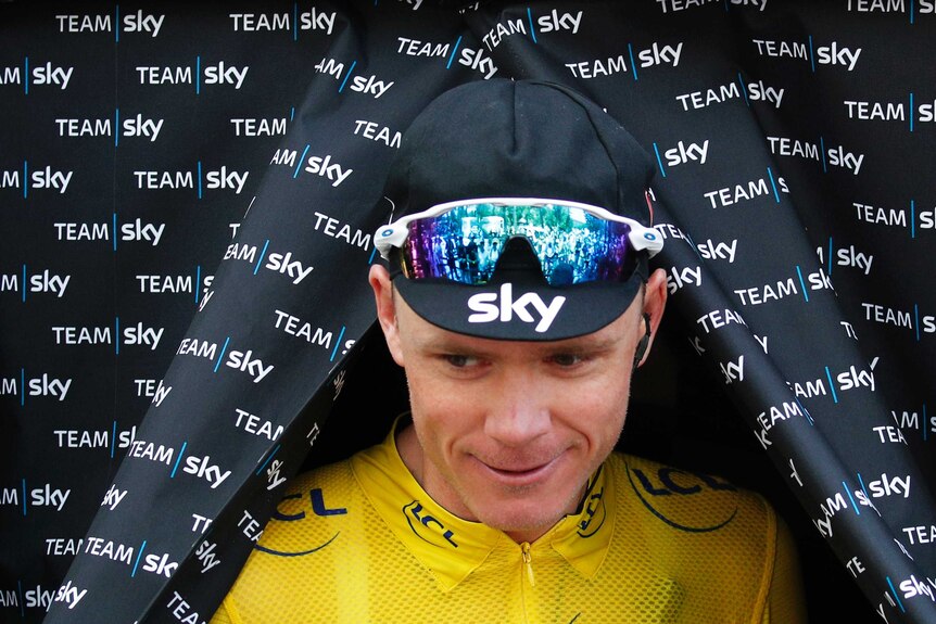 Team Sky cyclist Chris Froome emerges through a curtain wearing the yellow jersey