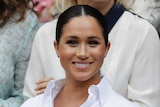 Meghan Markle smiles while sitting in the Royal Box at Wimbledon