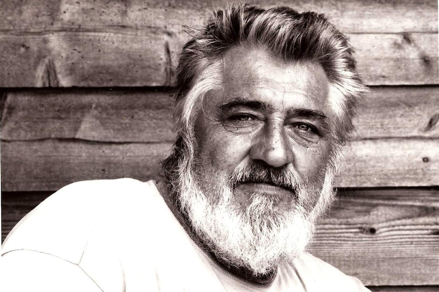 A black and white photo of an older, bearded man with silvery hair.