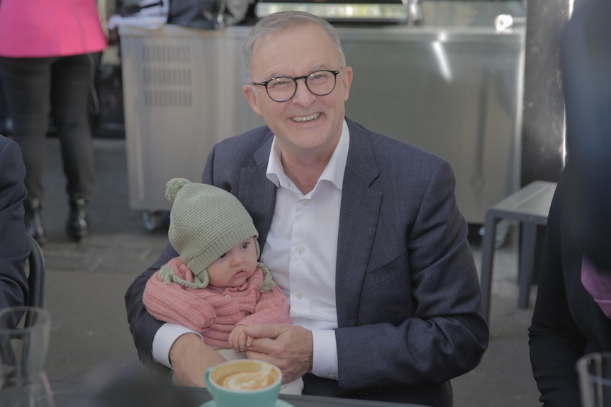 Labor leader Anthony Albanese holds a baby.