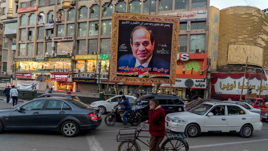 The photo of Egypt President Sisi is seen in a huge gold frame in a busy street.