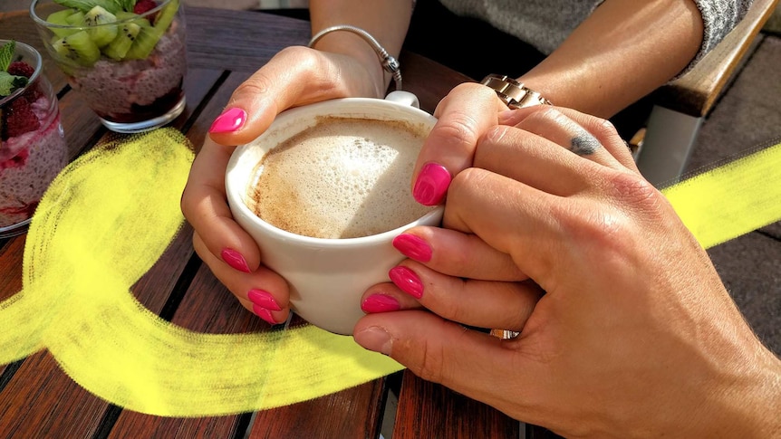 Woman and man holding hands with coffee on the table