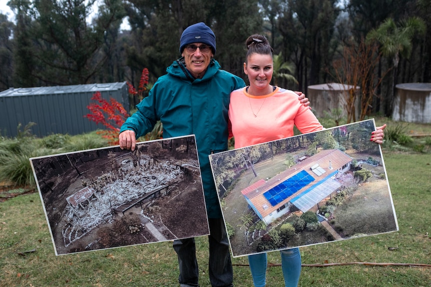 A man and a woman stand on a green property holding large posters