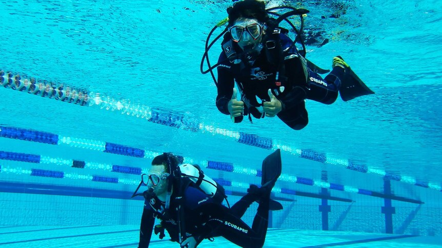 two people scuba diving in pool.
