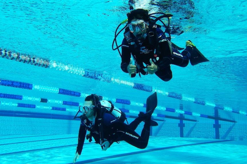 two people scuba diving in pool.
