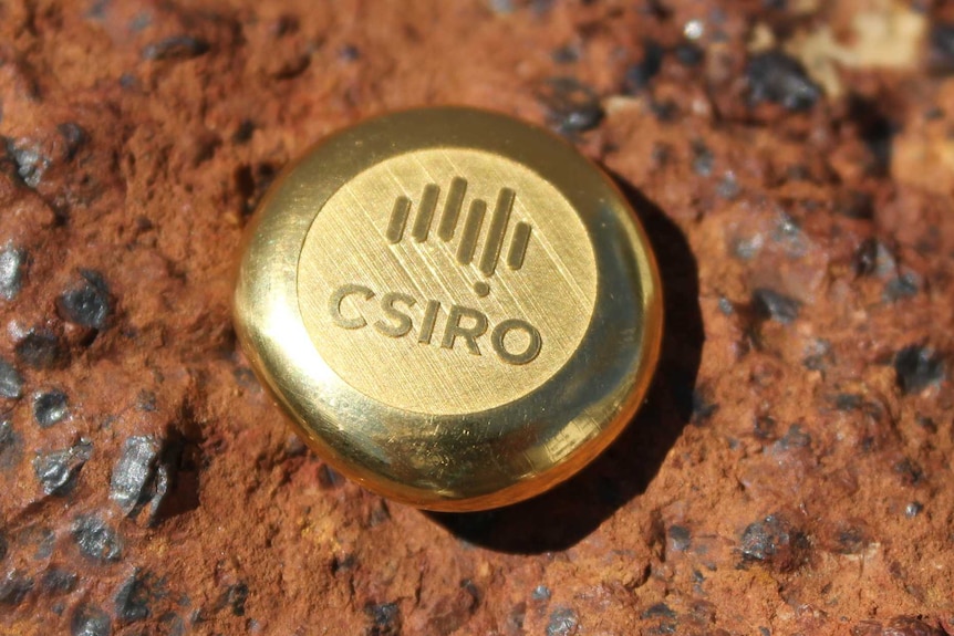 A circular gold ingot with the logo of the CSIRO on it