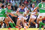 Kurt Mann runs with the ball under his left arm with Canberra Raiders players all around him