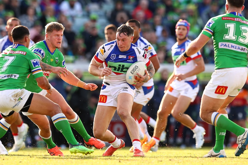 Kurt Mann runs with the ball under his left arm with Canberra Raiders players all around him