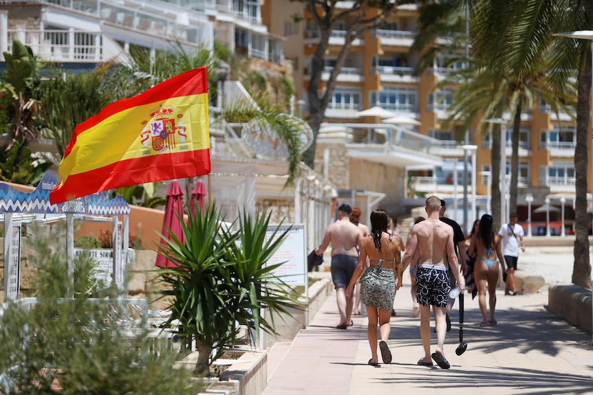 Tourists walk by the seafront at Magaluf beach in Spain on July 1, 2020.