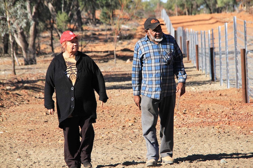 Les aînés autochtones Geraldine Robinson et John Bird marchent le long d'une clôture en grappe près de Cunnamulla, dans l'ouest du Queensland