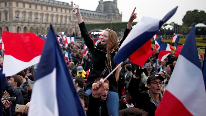 Supporters of Emmanuel Macron celebrate and wave flags near the Louvre museum after the French election results were announced.