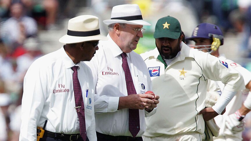Umpires Billy Doctrove (L) and Darrell Hair (C) show the ball to Pakistan's captain Inzamam-ul-Haq.