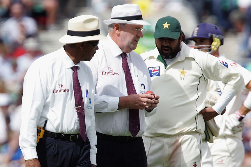 Umpires Billy Doctrove (L) and Darrell Hair (C) show the ball to Pakistan's captain Inzamam-ul-Haq.