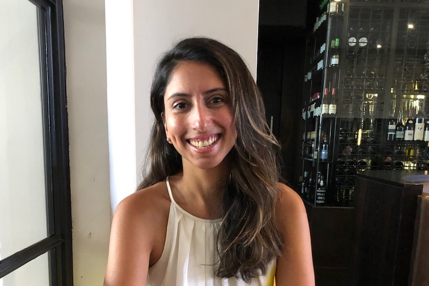 A woman smiles while sitting at a table in a restaurant