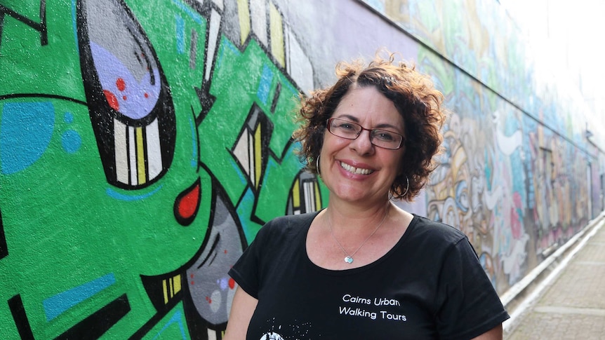 Woman standing in a laneway covered in street art.