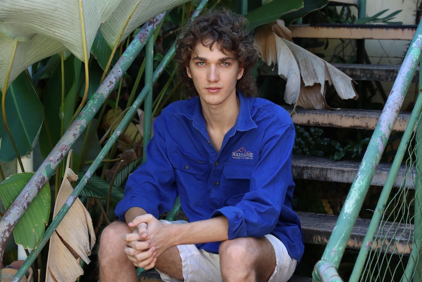 a young man sitting on a step in a yard