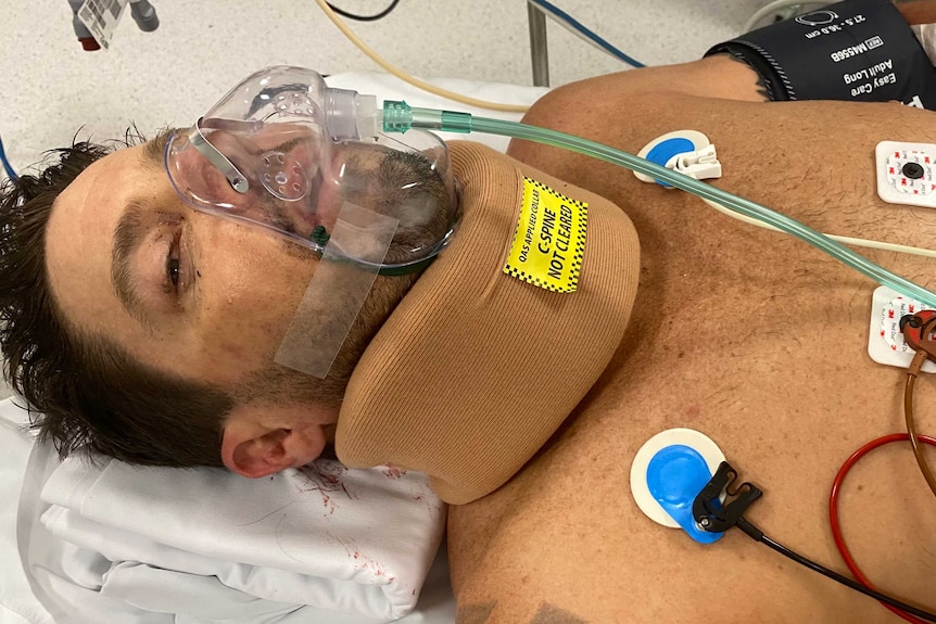 A man laying in a hospital bed wearing a breathing aparatus.