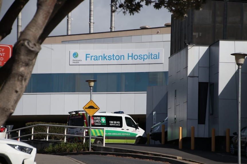 The exterior of a hospital building with an ambulance out the front.